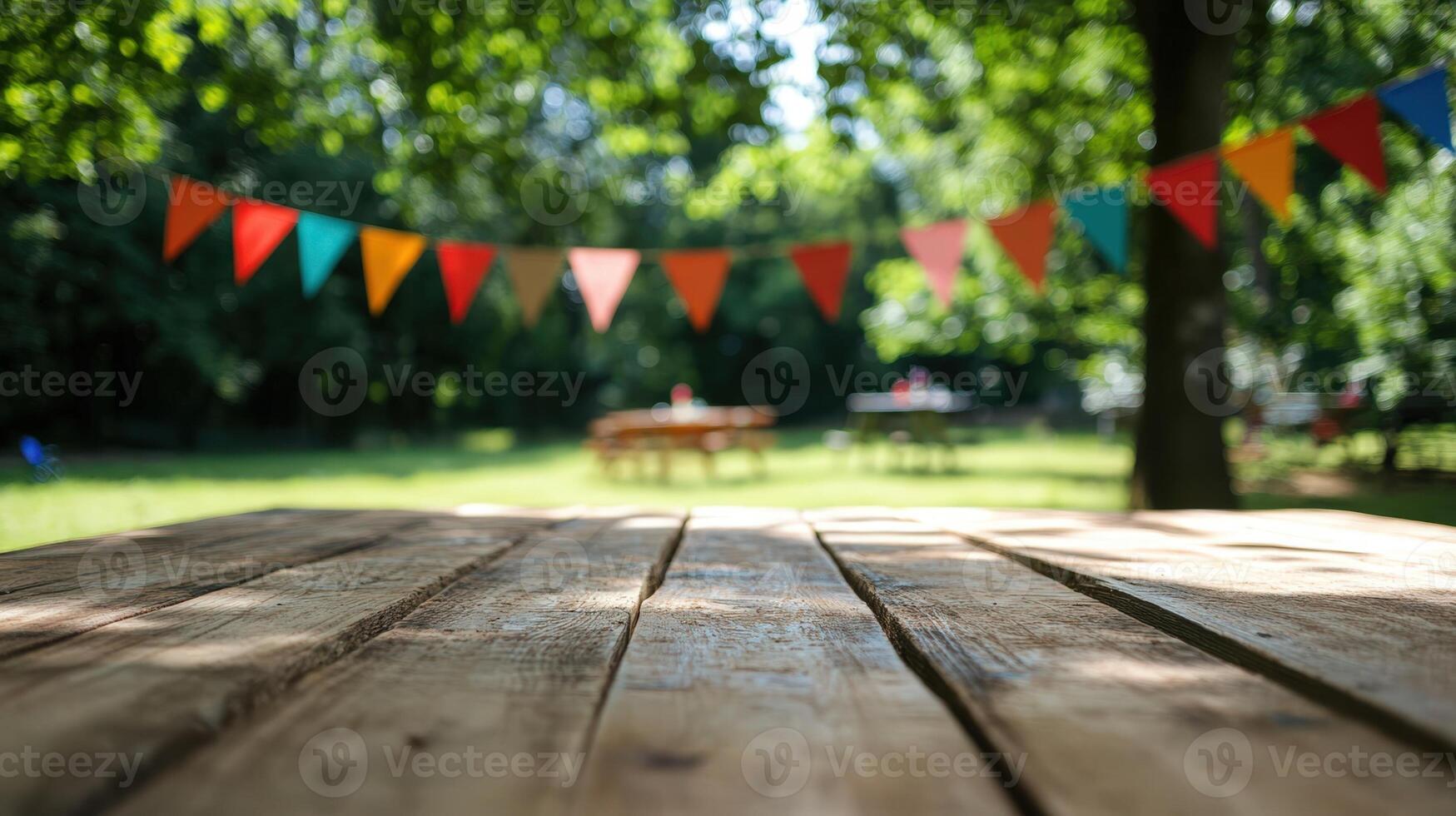 Empty wooden table top with a blurred background of colorful flags and a green tree photo