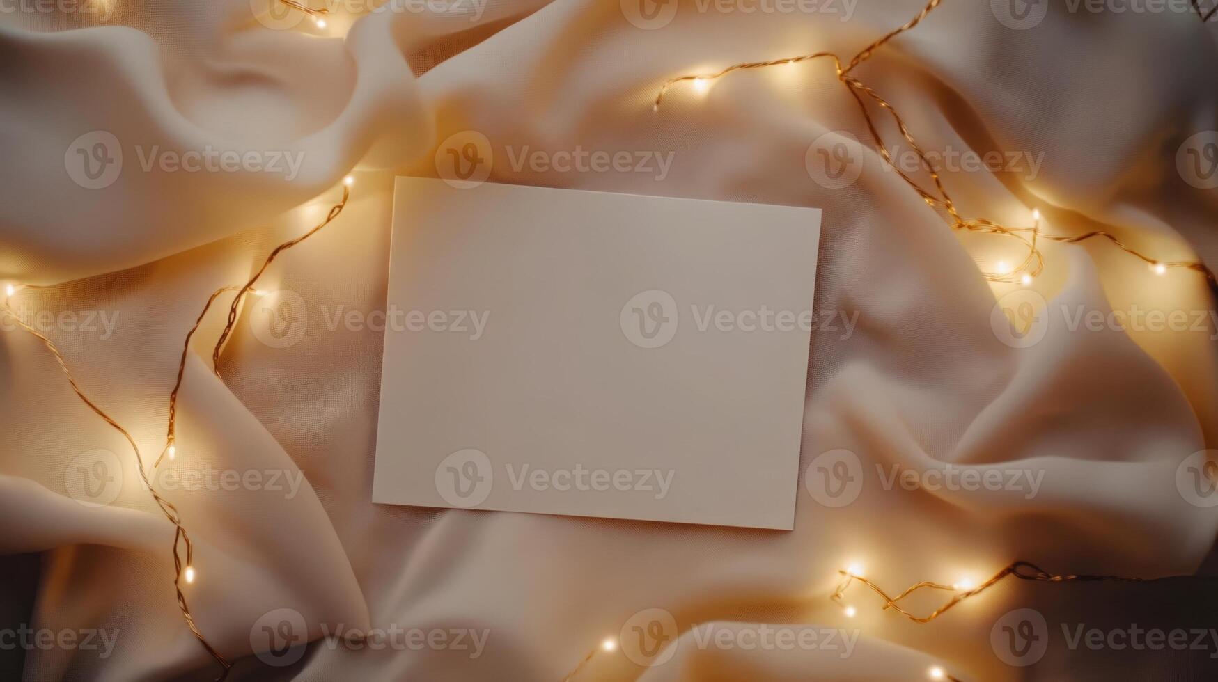 Blank card mockup lying on soft fabric, surrounded by warm fairy lights, highlighting festive atmosphere for personal messages or celebratory communication photo