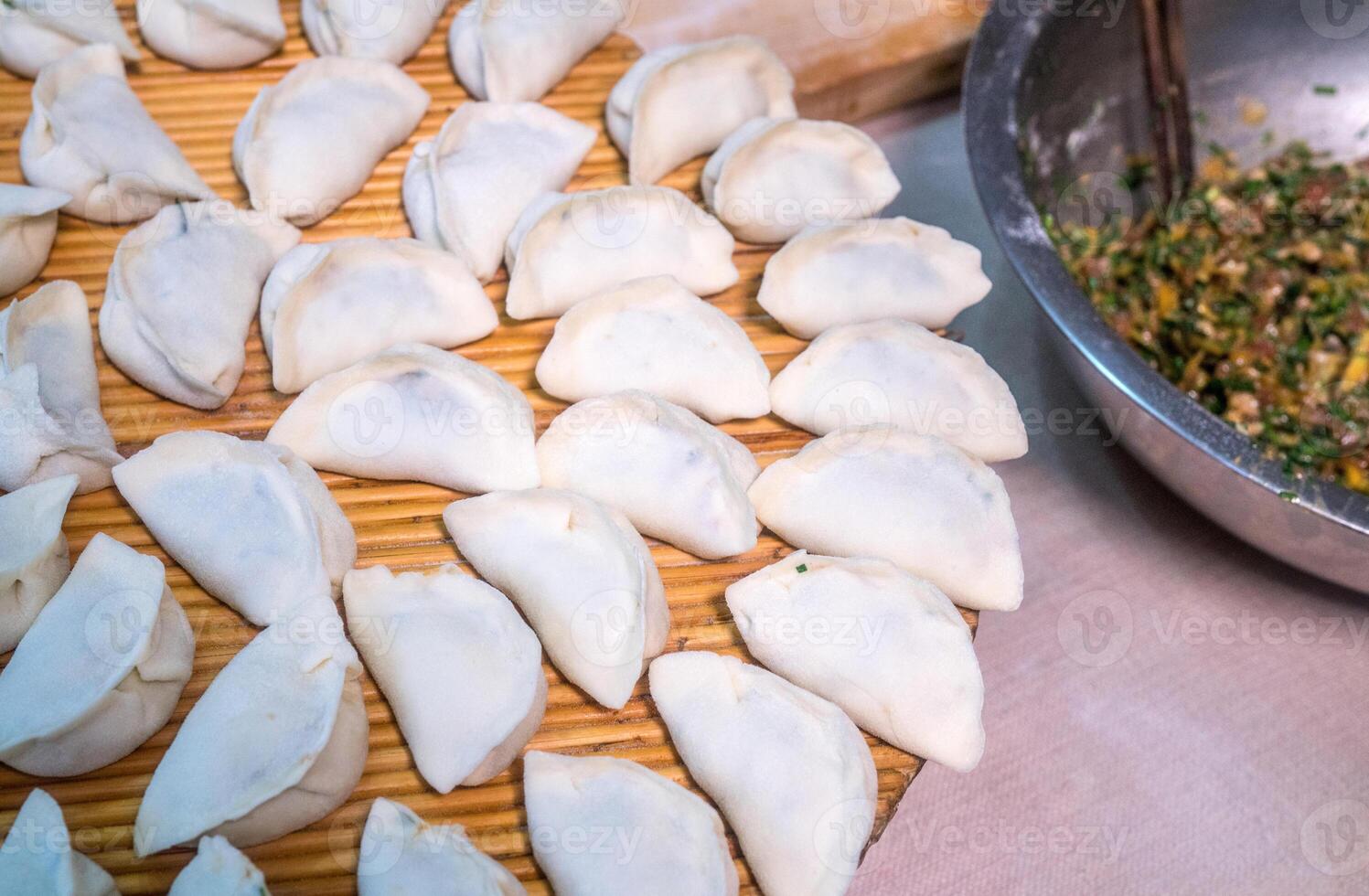 Raw Chinese dumplings on the reed plate ready for steaming photo