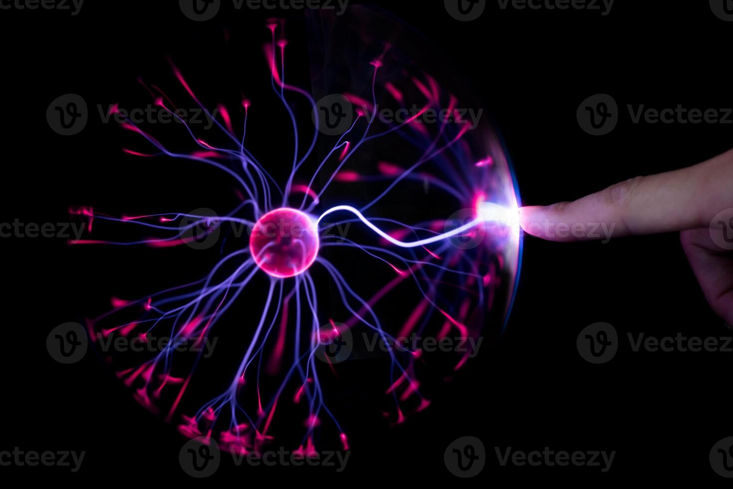 Finger touching plasma light ball on black background photo