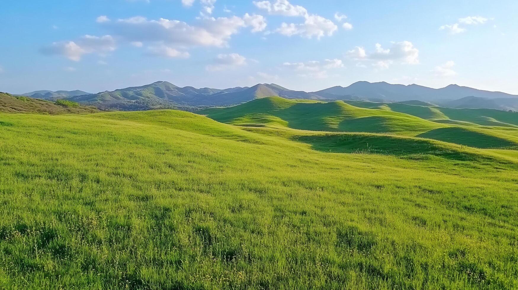 Lush green hills under a blue sky with distant mountains. photo