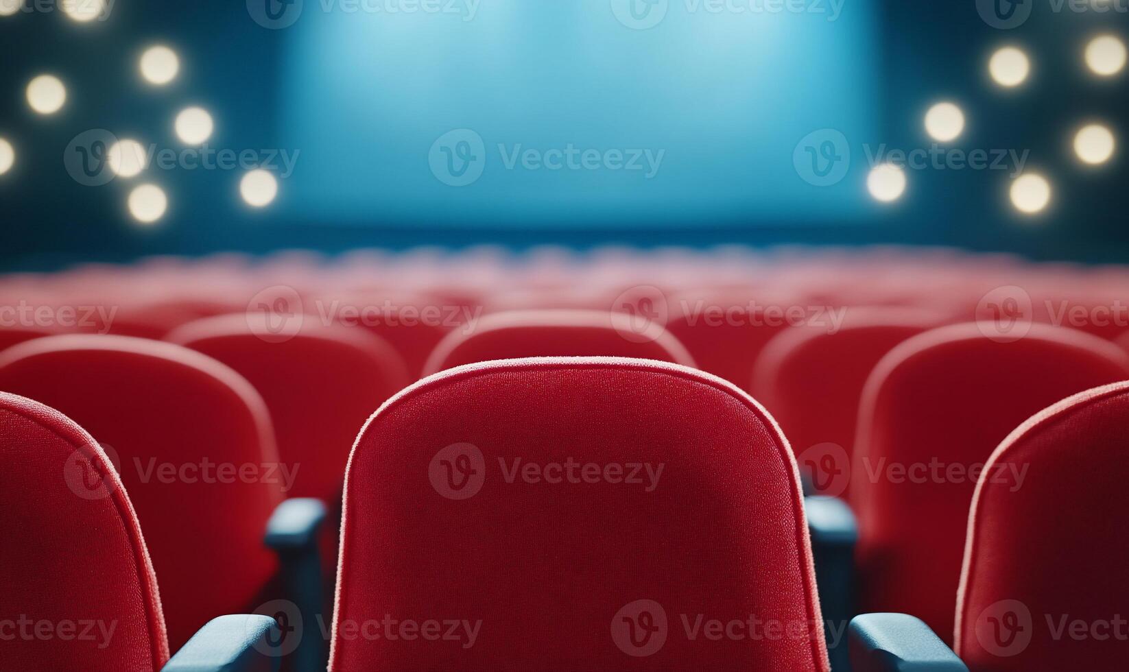 Empty red theater seats with a stage illuminated by soft lights. photo