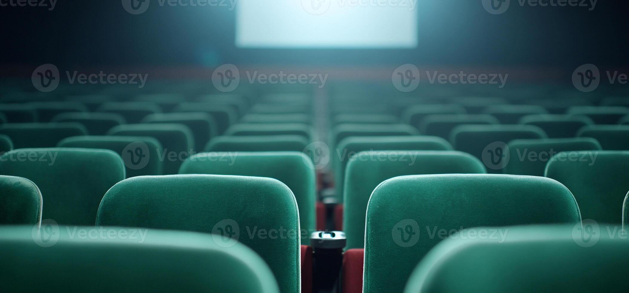 A row of empty green theater seats facing a projection screen. photo
