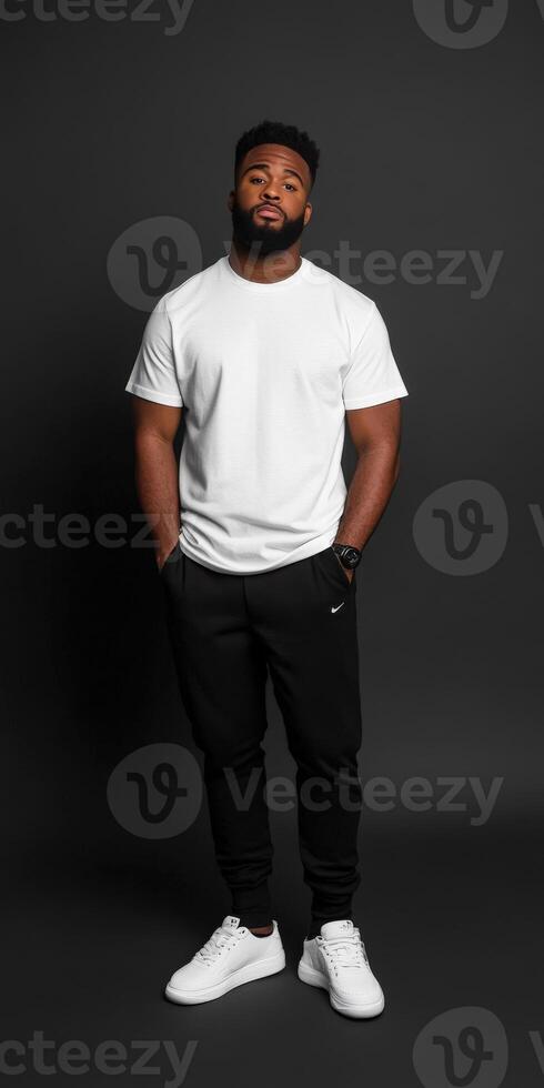Man in casual outfit poses confidently against dark backdrop photo