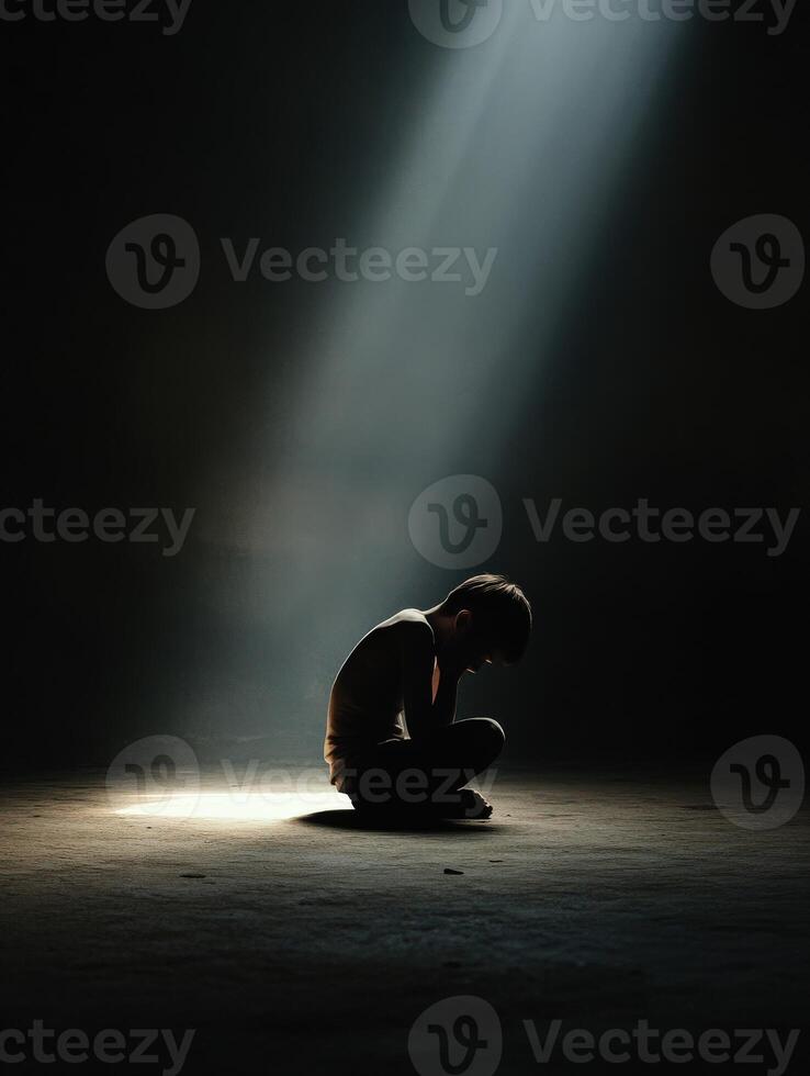 Boy in a dimly lit space reflecting in a beam of light photo