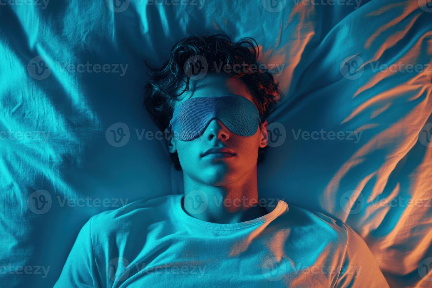 Young man resting comfortably with sleep mask while lying on bed at night photo