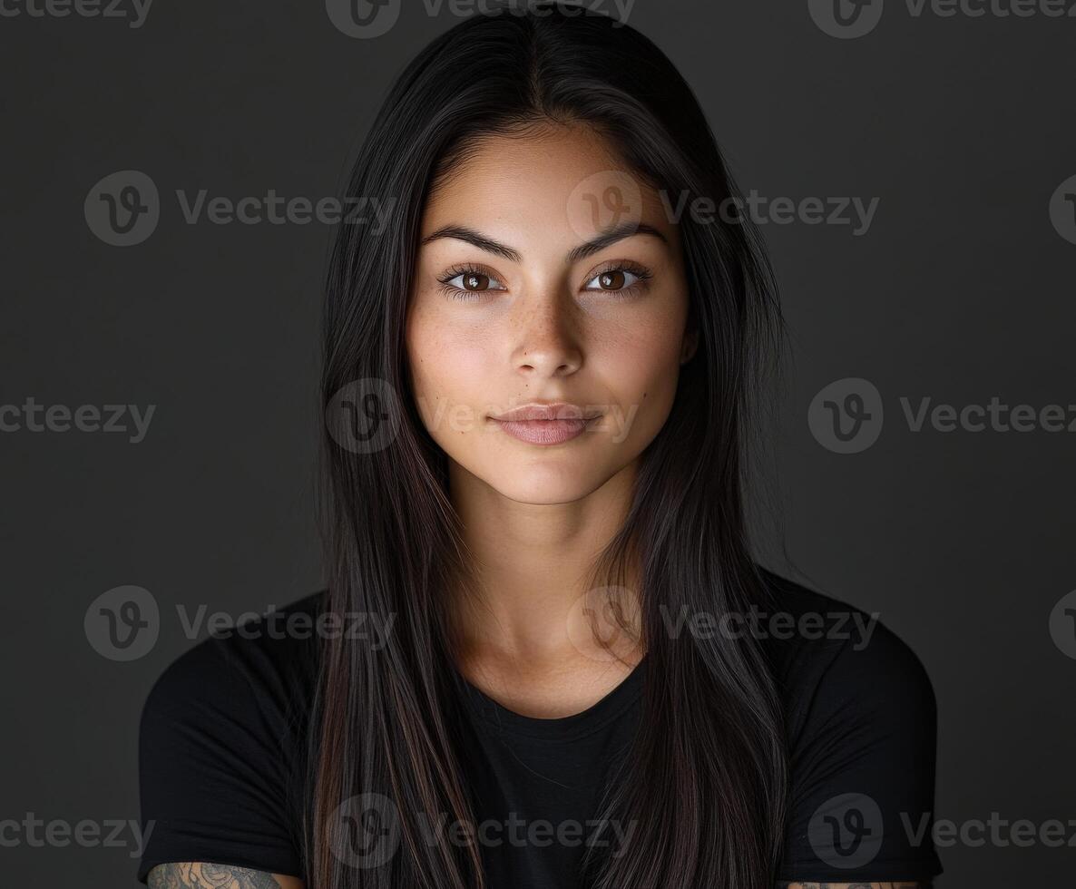 Portrait of a young woman with long hair and tattoos against a dark background photo