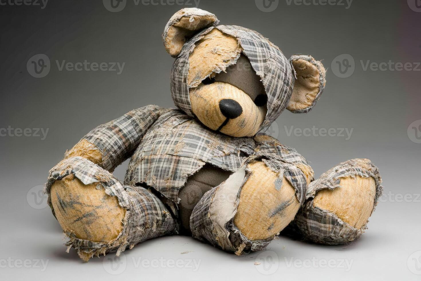 Worn teddy bear with patchy clothing sitting against a neutral background photo