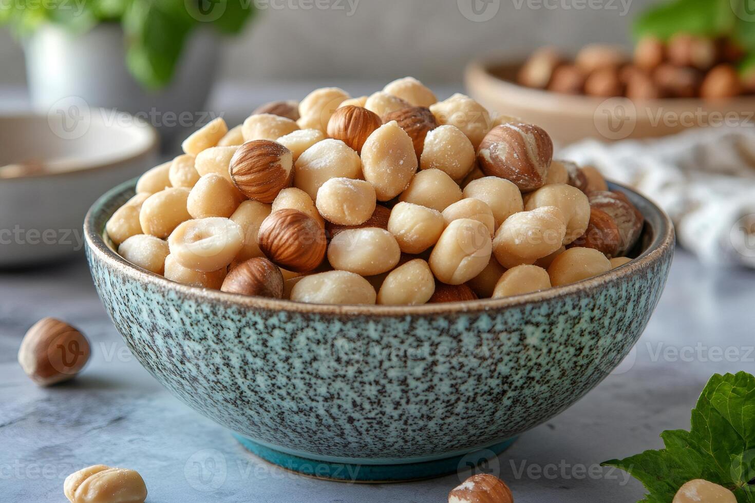 Macadamia and hazelnuts filling a teal bowl on a kitchen counter photo