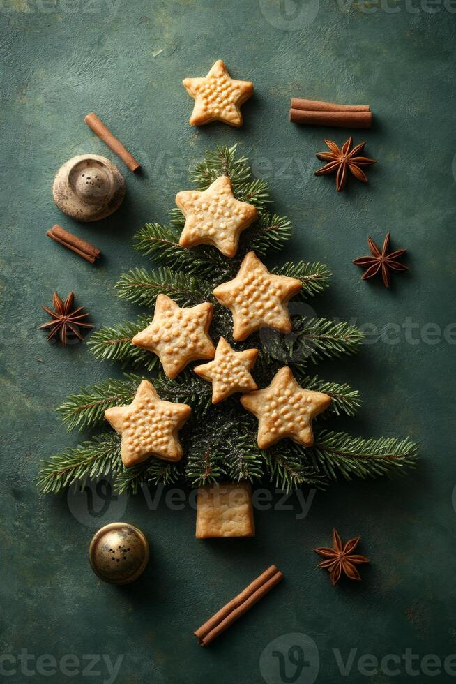 Christmas tree made of fir branches and star shaped cookies decorated with cinnamon sticks and anise stars on green background photo