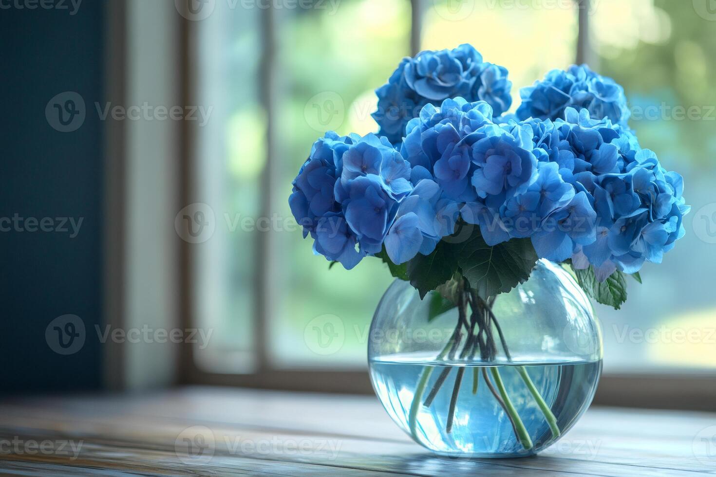 Bouquet of blue hydrangeas flowers in glass vase on wooden table by window photo