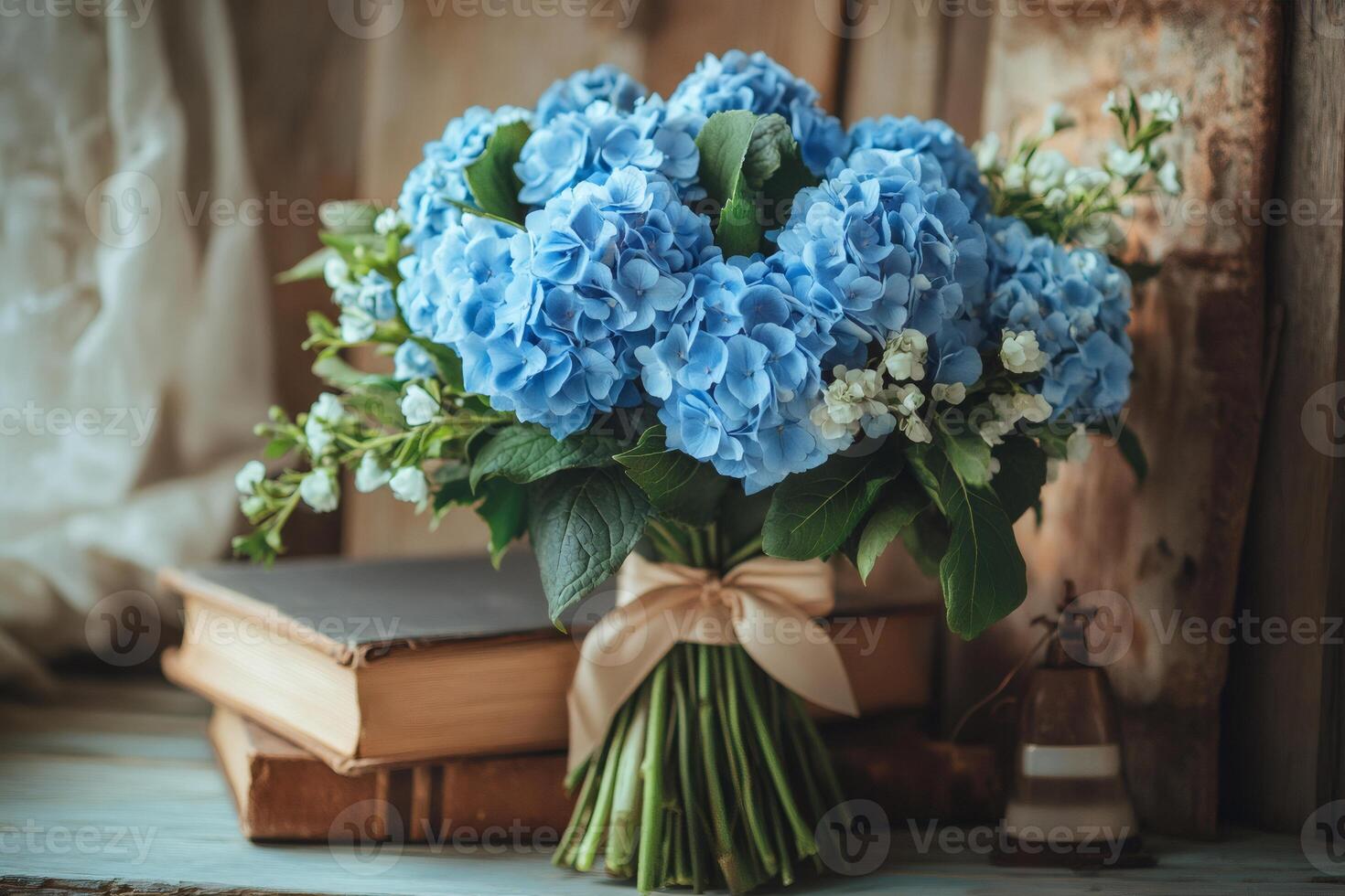 Bouquet of blue hydrangeas with satin ribbon near old books photo