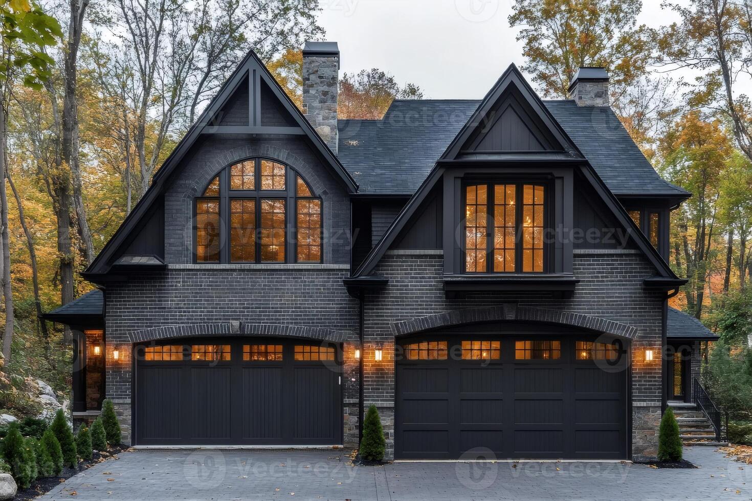 Modern black brick house with glowing windows at twilight in autumn photo