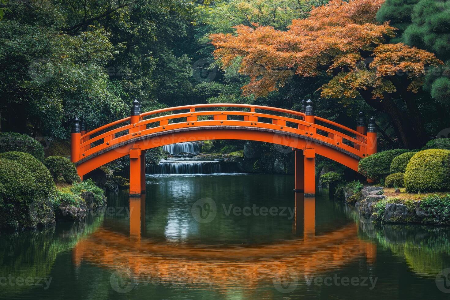 Orange wooden arch bridge reflecting on calm water in japanese garden photo