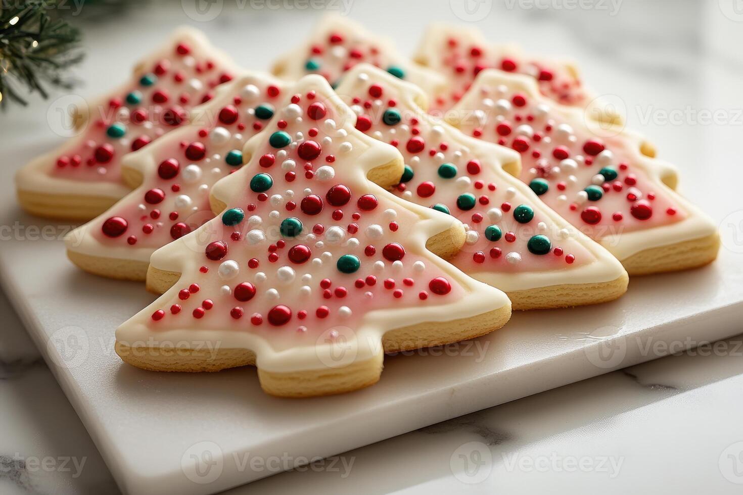 Christmas tree shaped sugar cookies decorated with icing and sprinkles resting on marble tray photo