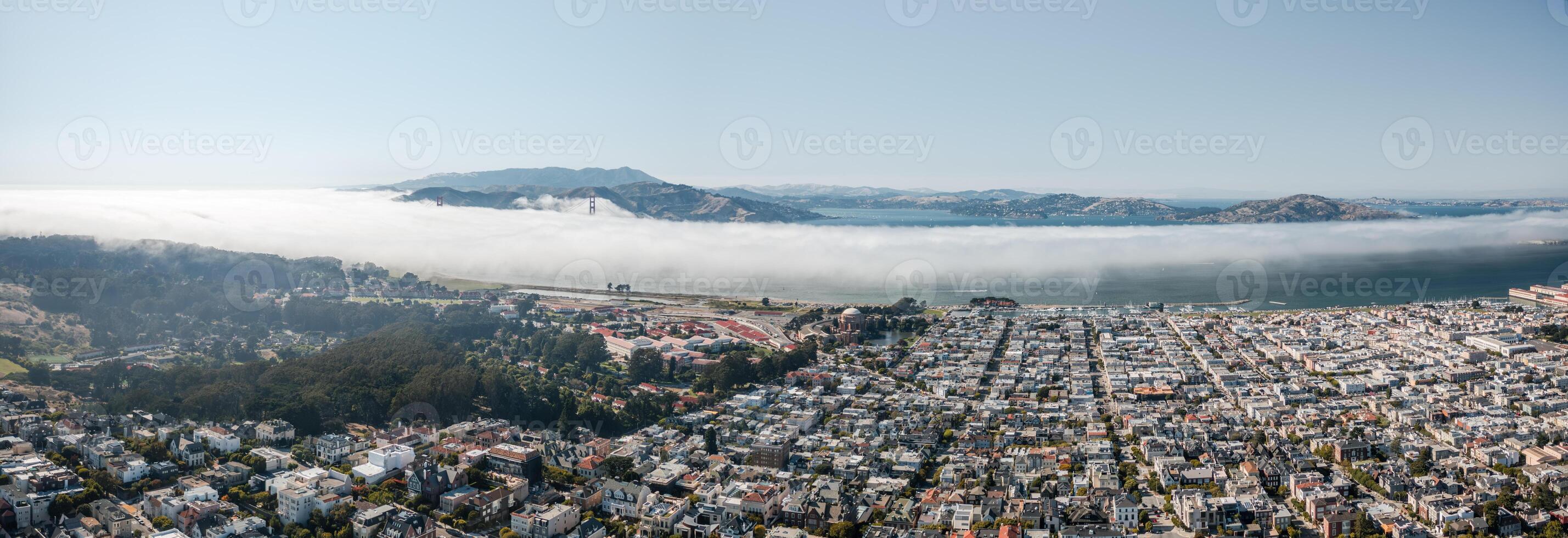 Panoramic aerial view of San Francisco showcasing cityscape against a backdrop of fog surrounding the Golden Gate Bridge photo