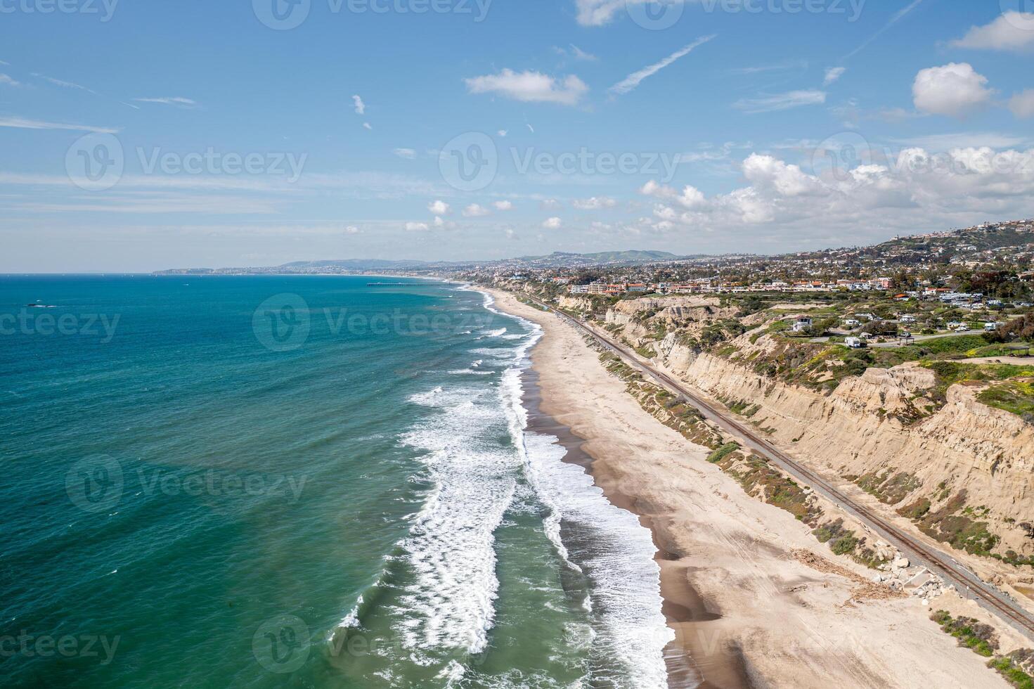 Expansive aerial view of San Clemente coastline with waves crashing on sandy beach under a clear sky photo