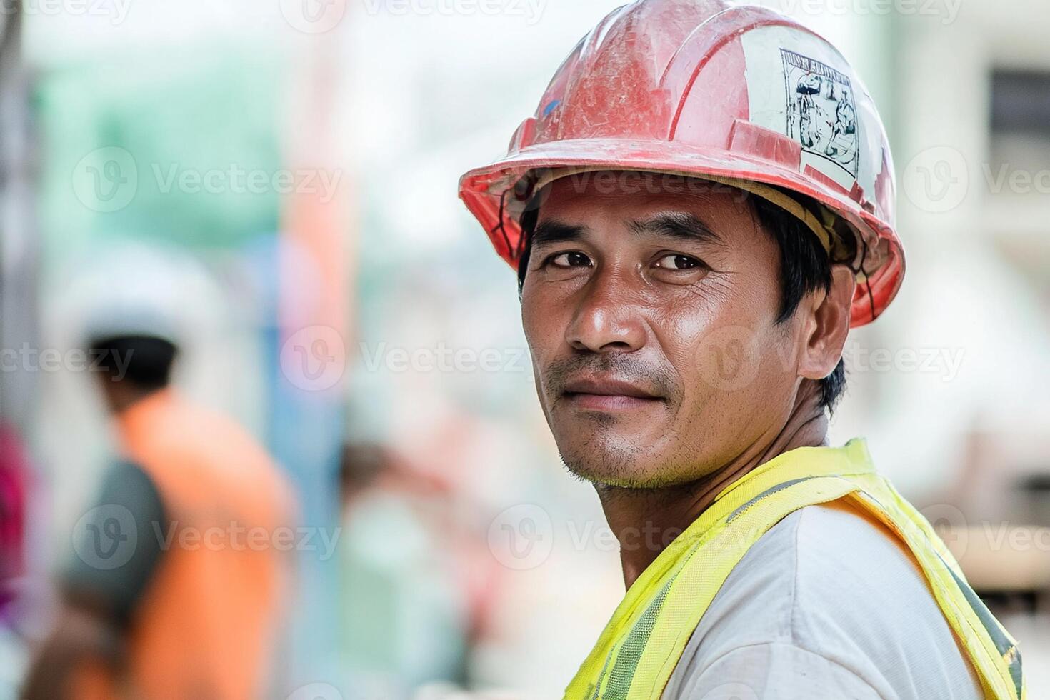 A man in a hard hat and vest standing in front of a construction site photo