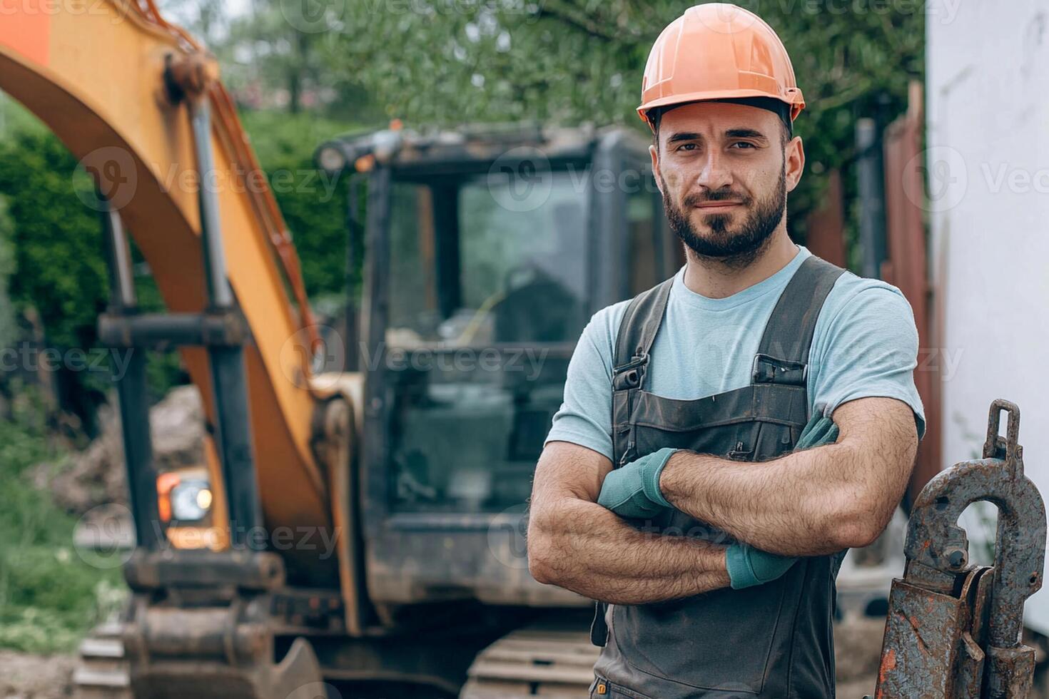 A man in overalls and hard hat standing in front of a construction machine photo
