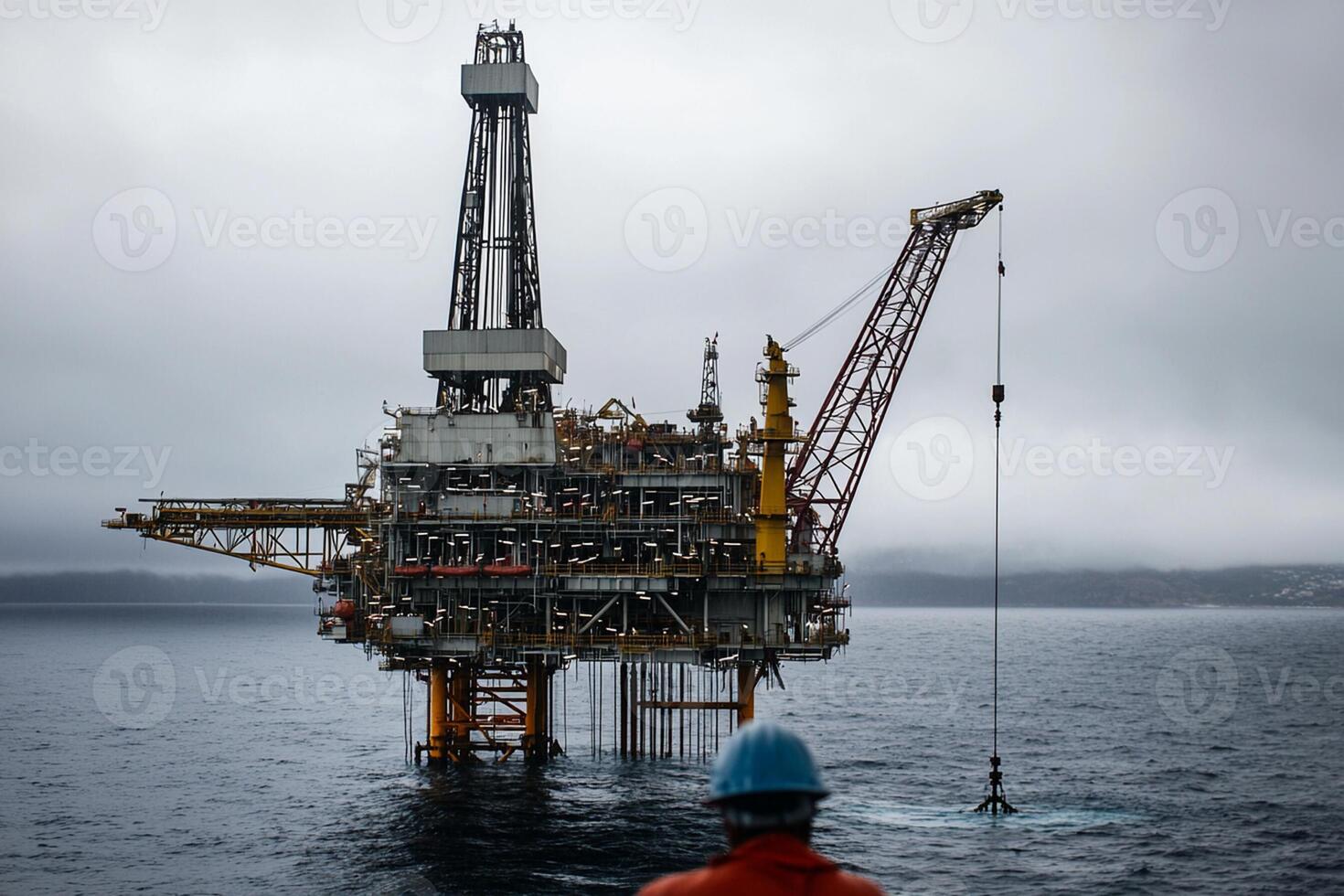 A man in an orange shirt standing on an oil rig photo
