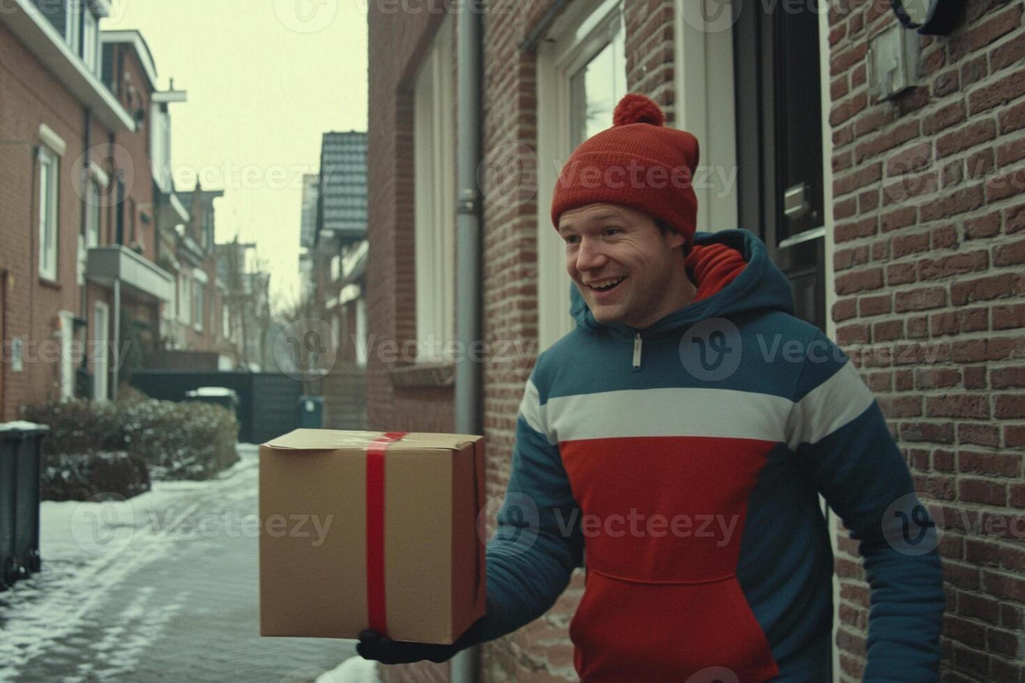 A man in a red hat and jacket holding a box photo