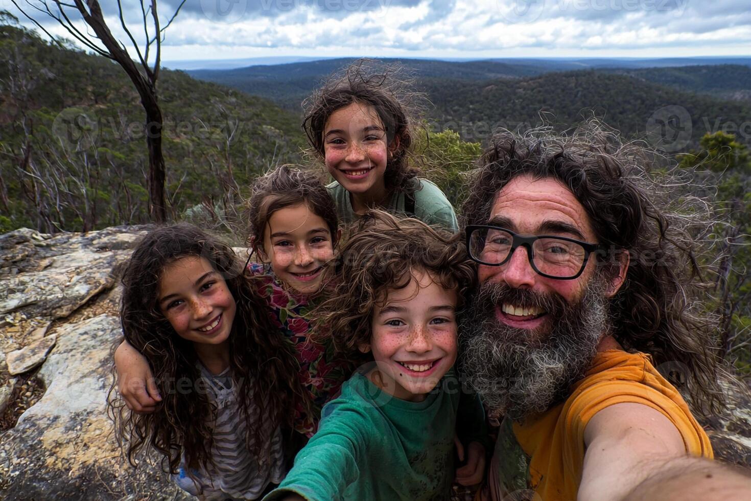 A man and four children taking a selfie on a mountain photo