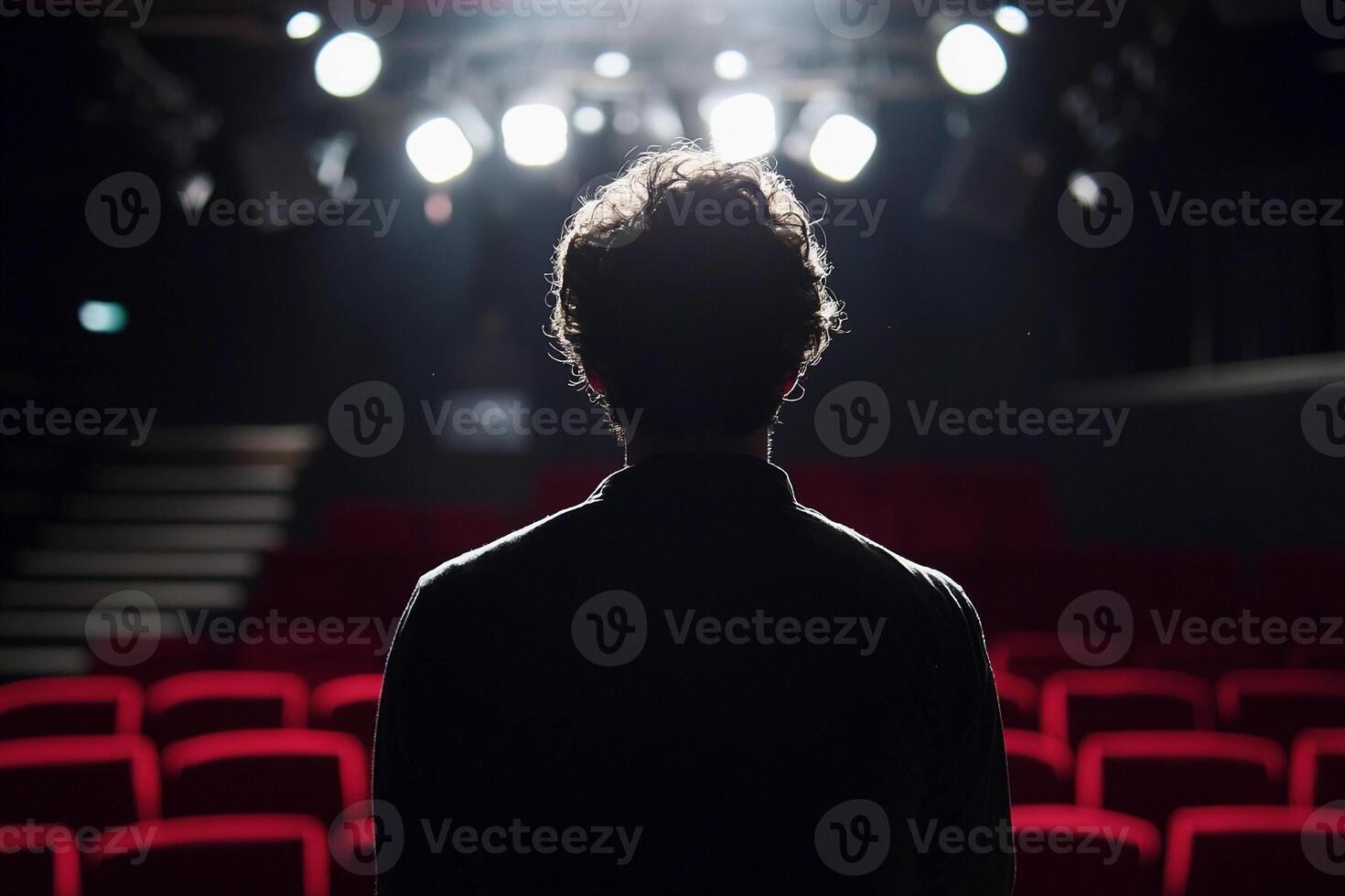 A man standing in front of a theater with red seats photo