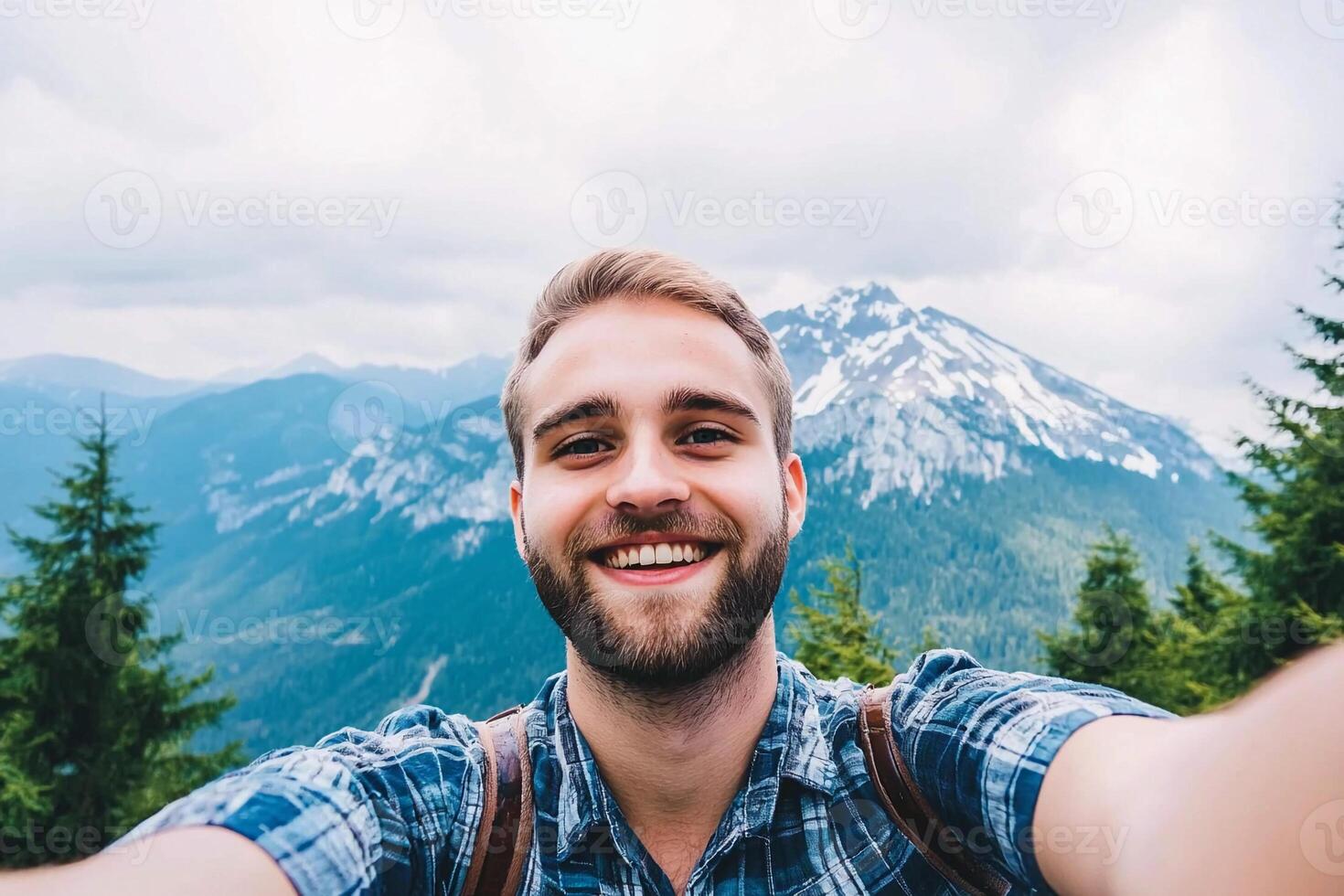 A man taking a selfie with a mountain in the background photo