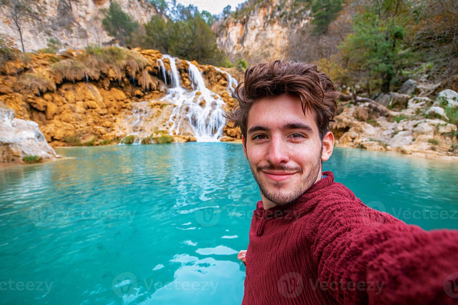 A man taking a selfie in front of a waterfall photo
