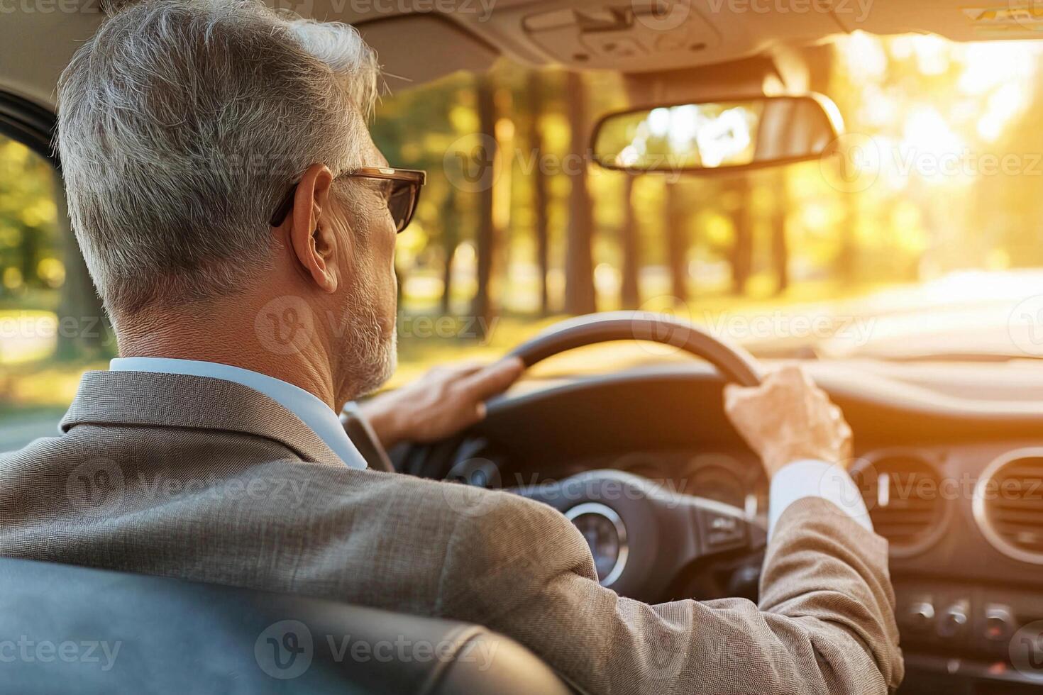 A man driving a car with the sun shining through the trees photo