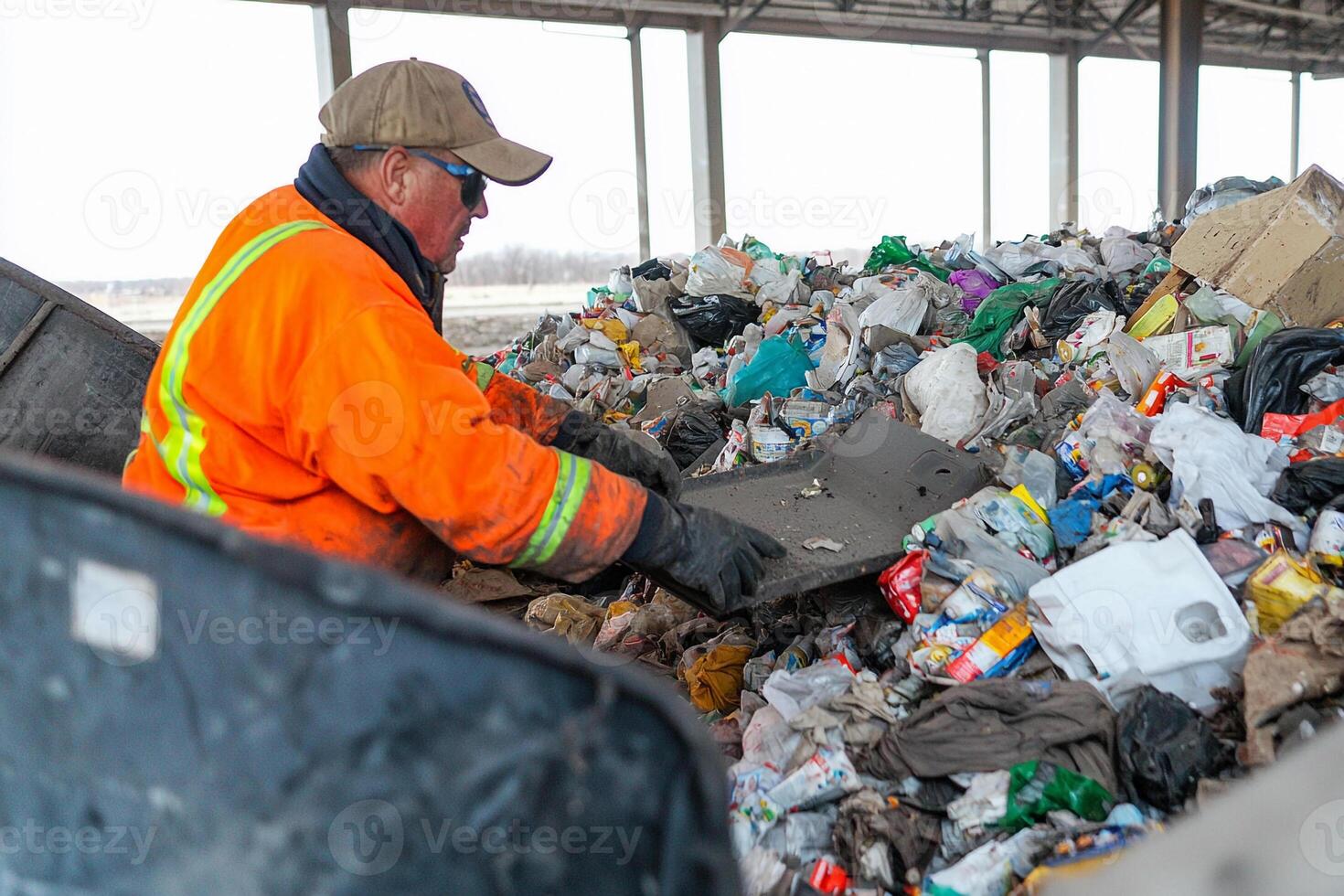 A man in an orange shirt is sorting through trash photo