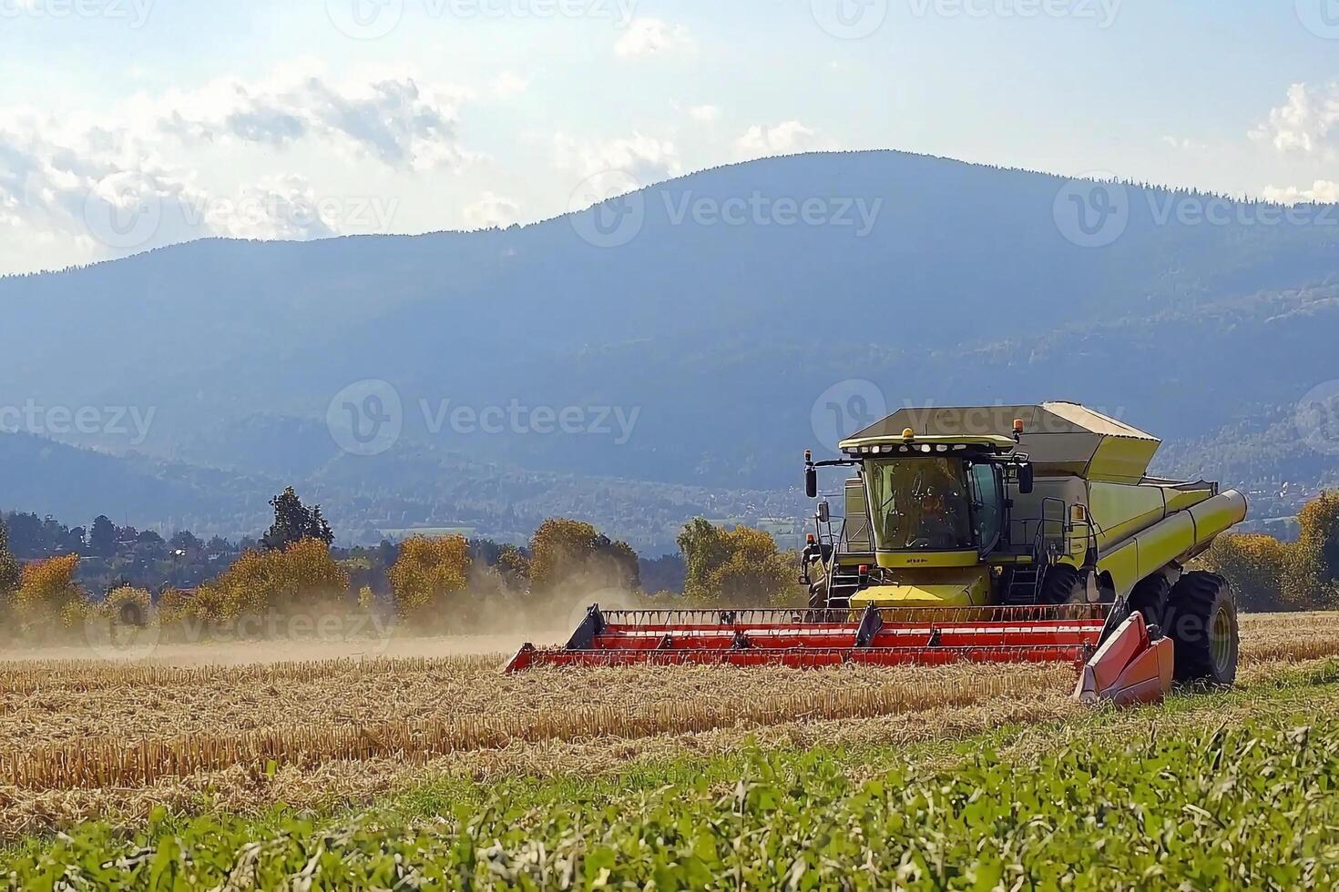 A combine harvester in a field with mountains in the background photo