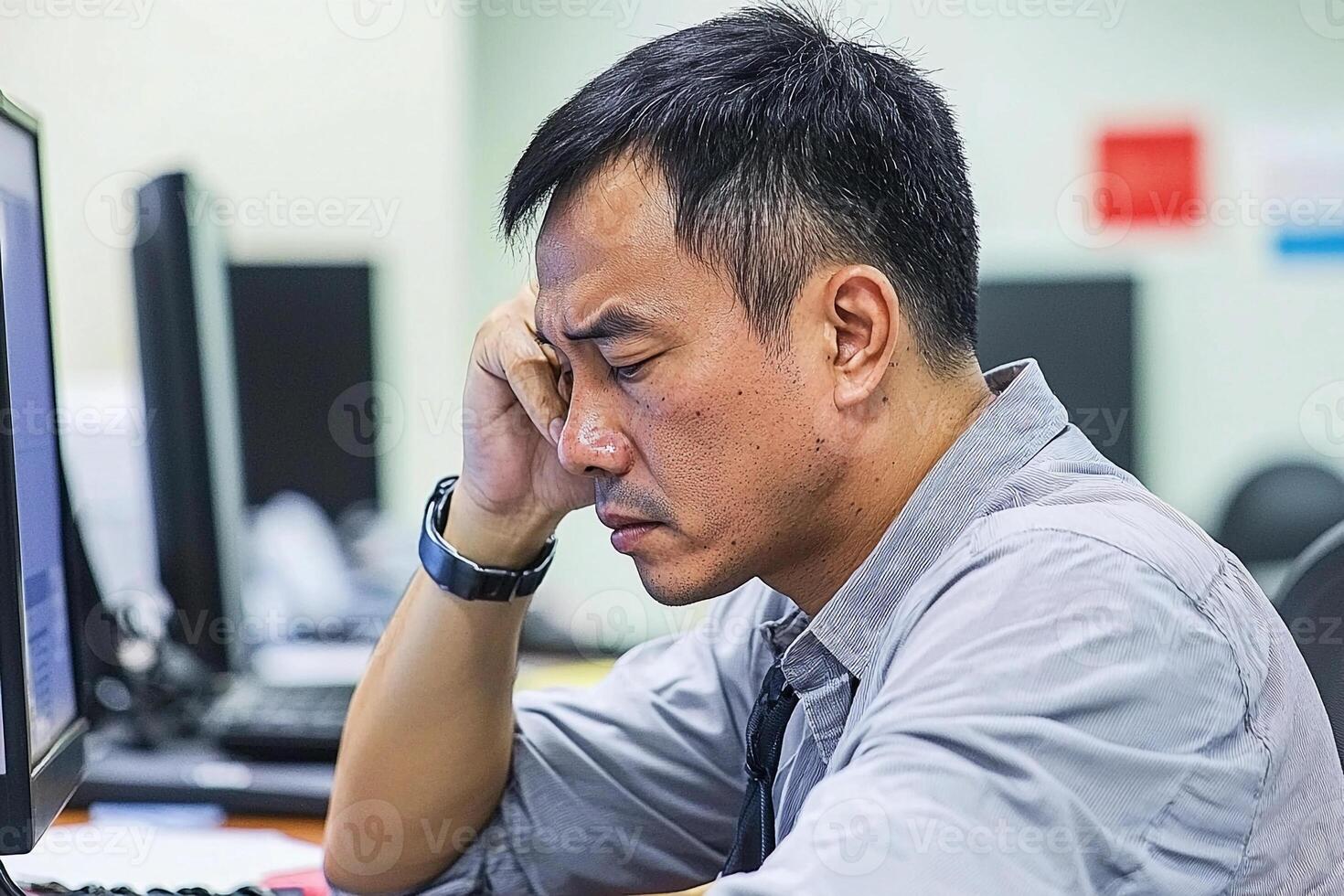 A man sitting at a desk with his head in his hands photo