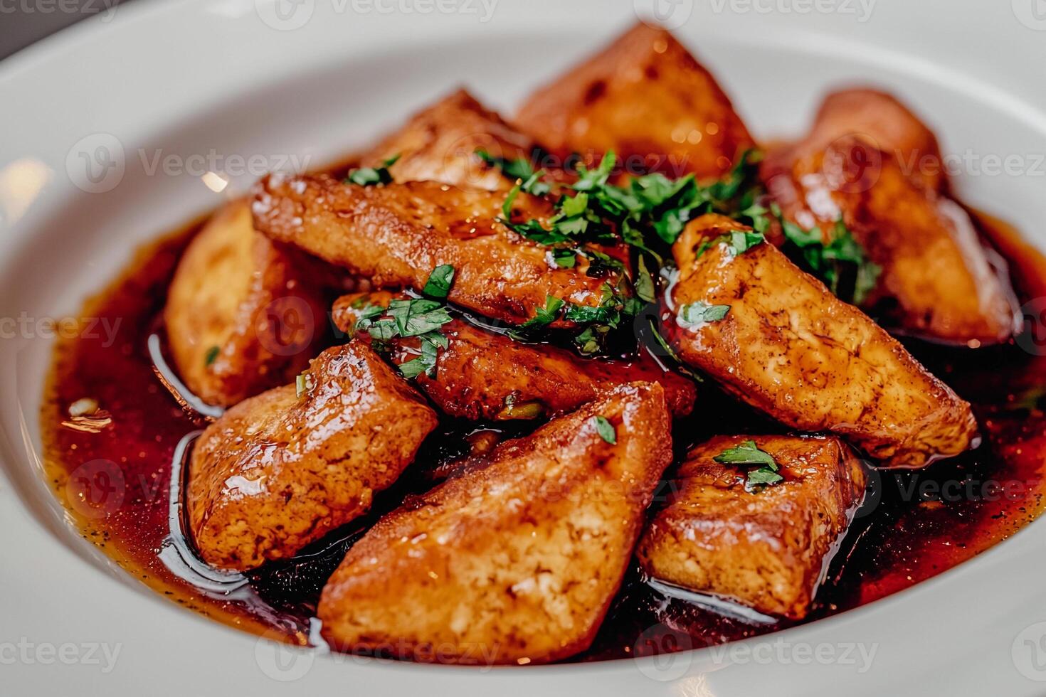 A plate of fried tofu with sauce and herbs photo