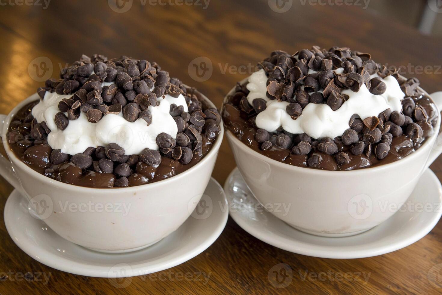 Two cups of chocolate pudding topped with whipped cream photo