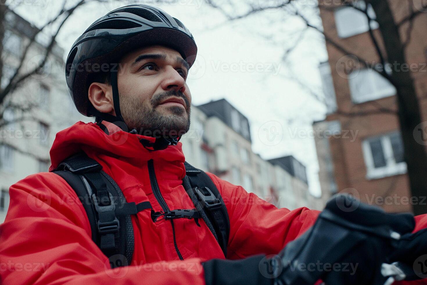 A man in a red jacket and helmet on a bicycle photo