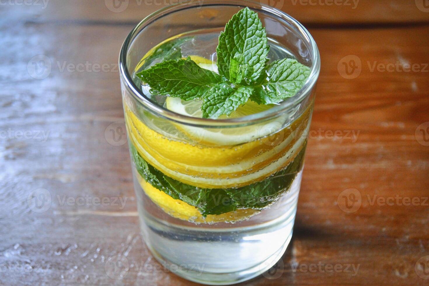 A glass of water with lemon slices and mint leaves photo
