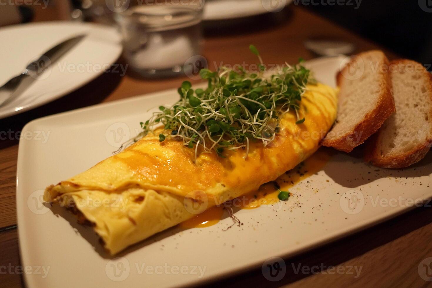 A white plate topped with an omelet and bread photo