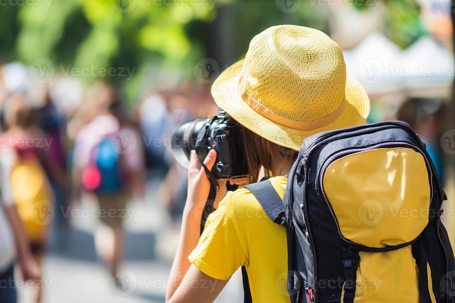 A woman with a yellow hat and backpack taking a picture photo