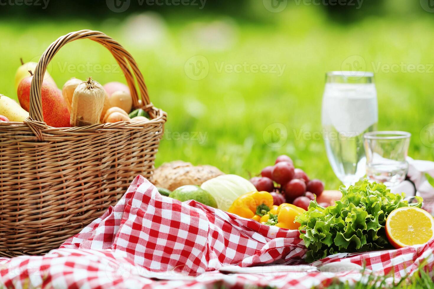 A picnic basket with fruits and vegetables on the grass photo