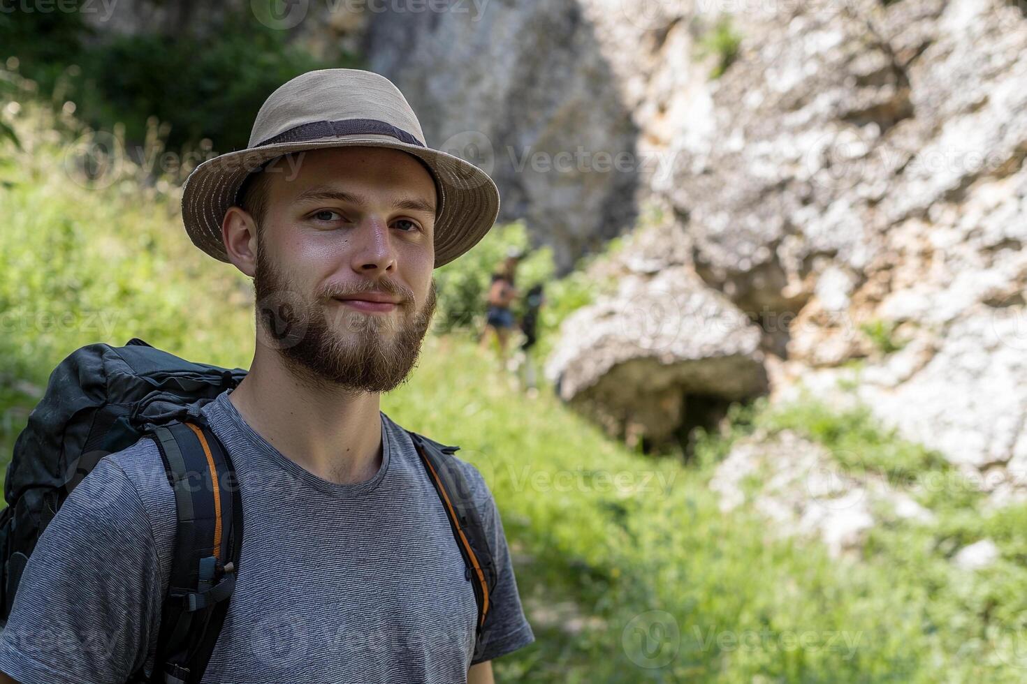 A man with a hat and backpack standing in the woods photo