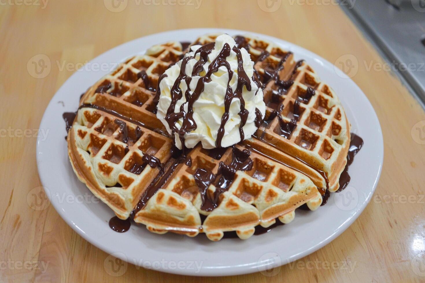 A waffle with whipped cream and chocolate syrup photo