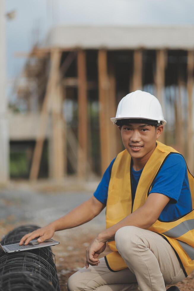 Asian man architect holds blueprint with skyscraper background, Asian male architect builder engineer design working planning confident outdoors in construction site. photo