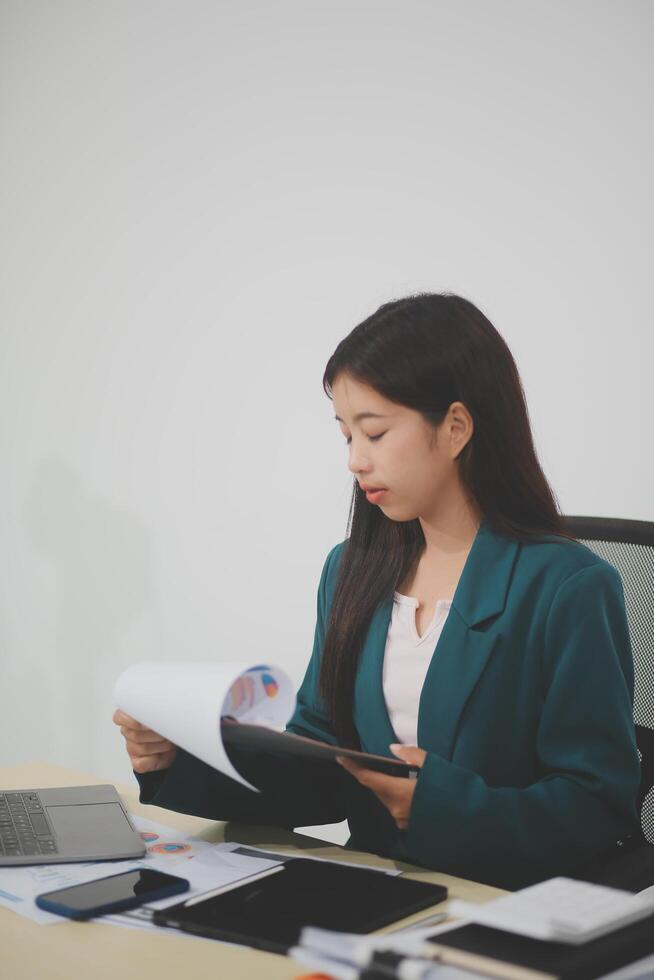 Asian business woman working using laptop computer, marketing report with calculator document on table Planning to analyze financial reports Investing in an online business plan, e-commerce. photo