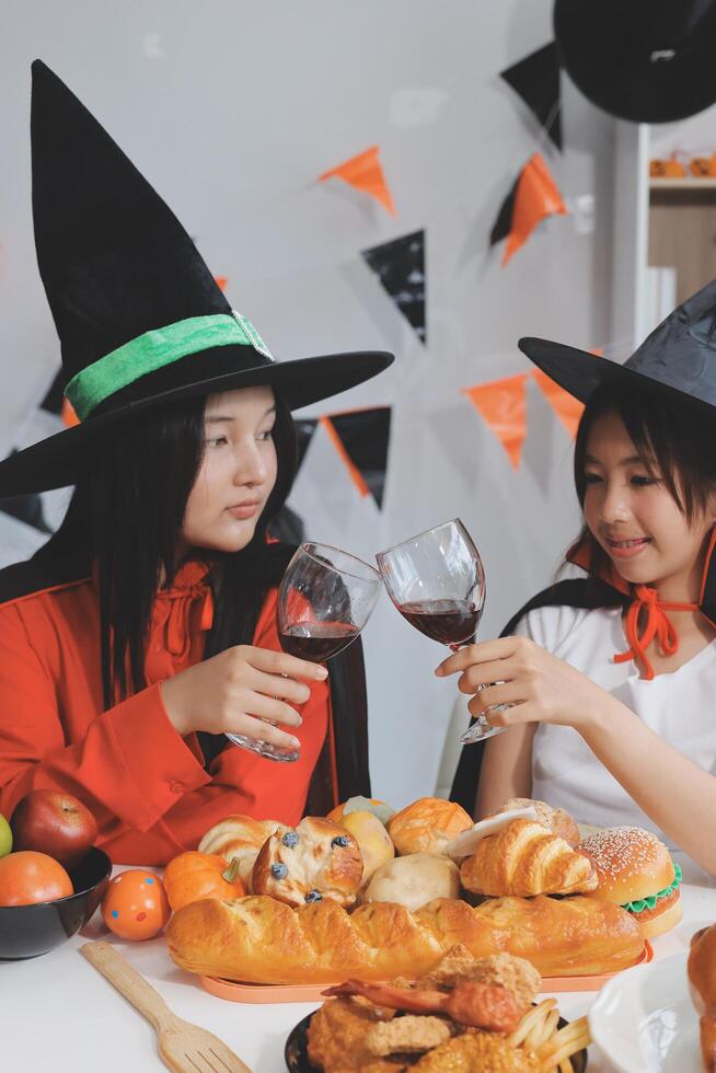 friendship, holiday and people concept - group of happy smiling friends in halloween costumes of vampire, devil, witch and cheetah at home party photo
