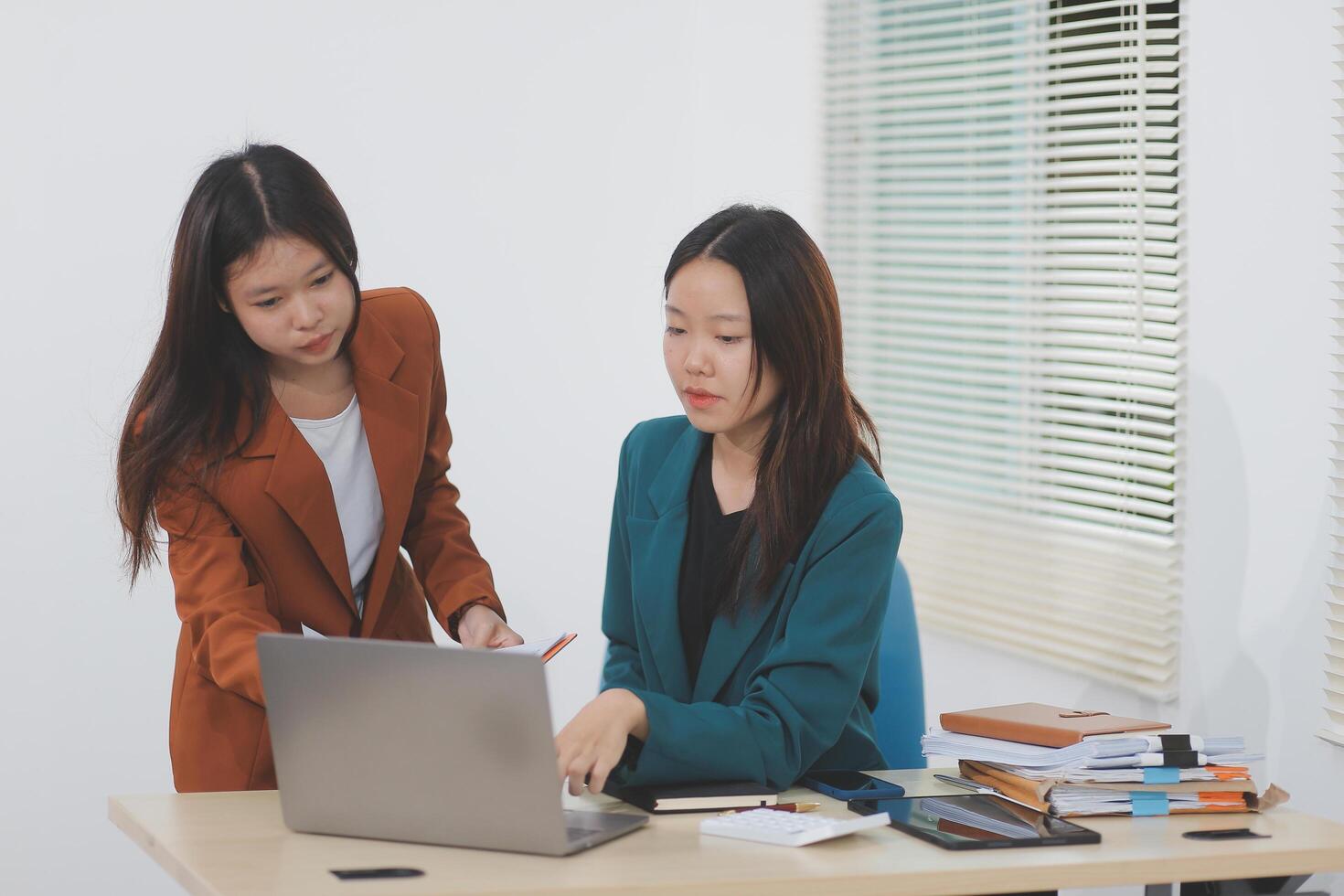 Two young Asian businesswoman discuss investment project working and planning strategy. Business people talking together with laptop computer at office. photo