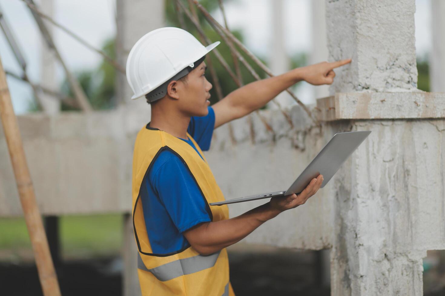 Young handsome asian civil engineer holding tablet looking forward and thinking, planning on construction building background. Evolution construction concept. photo