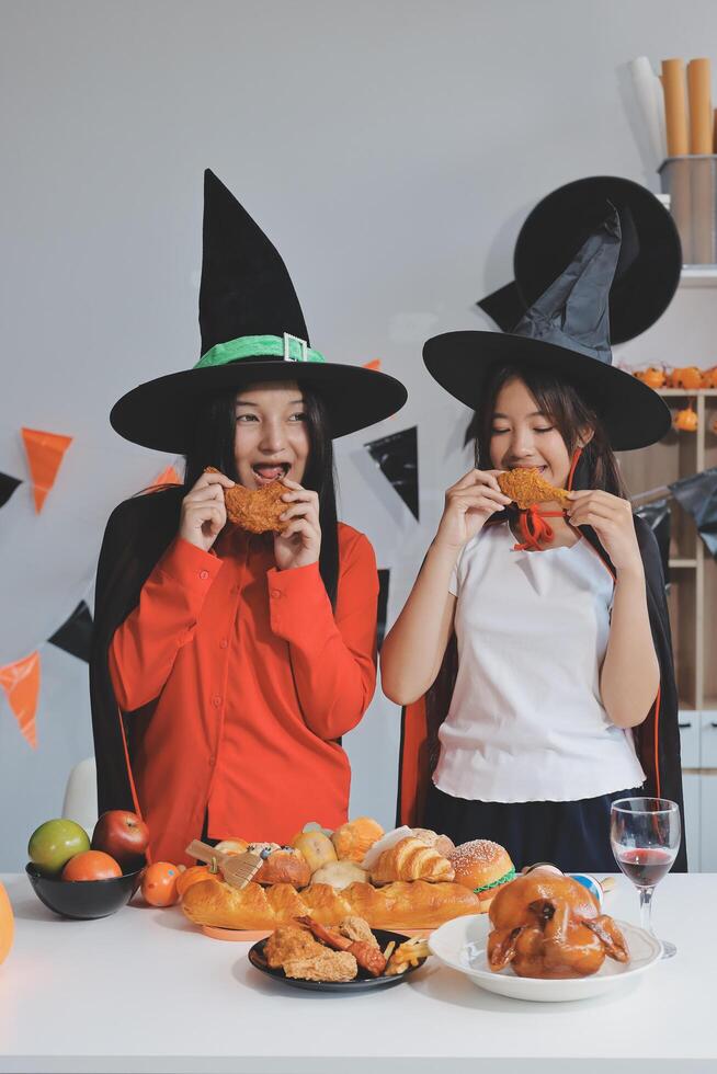 friendship, holiday and people concept - group of happy smiling friends in halloween costumes of vampire, devil, witch and cheetah at home party photo
