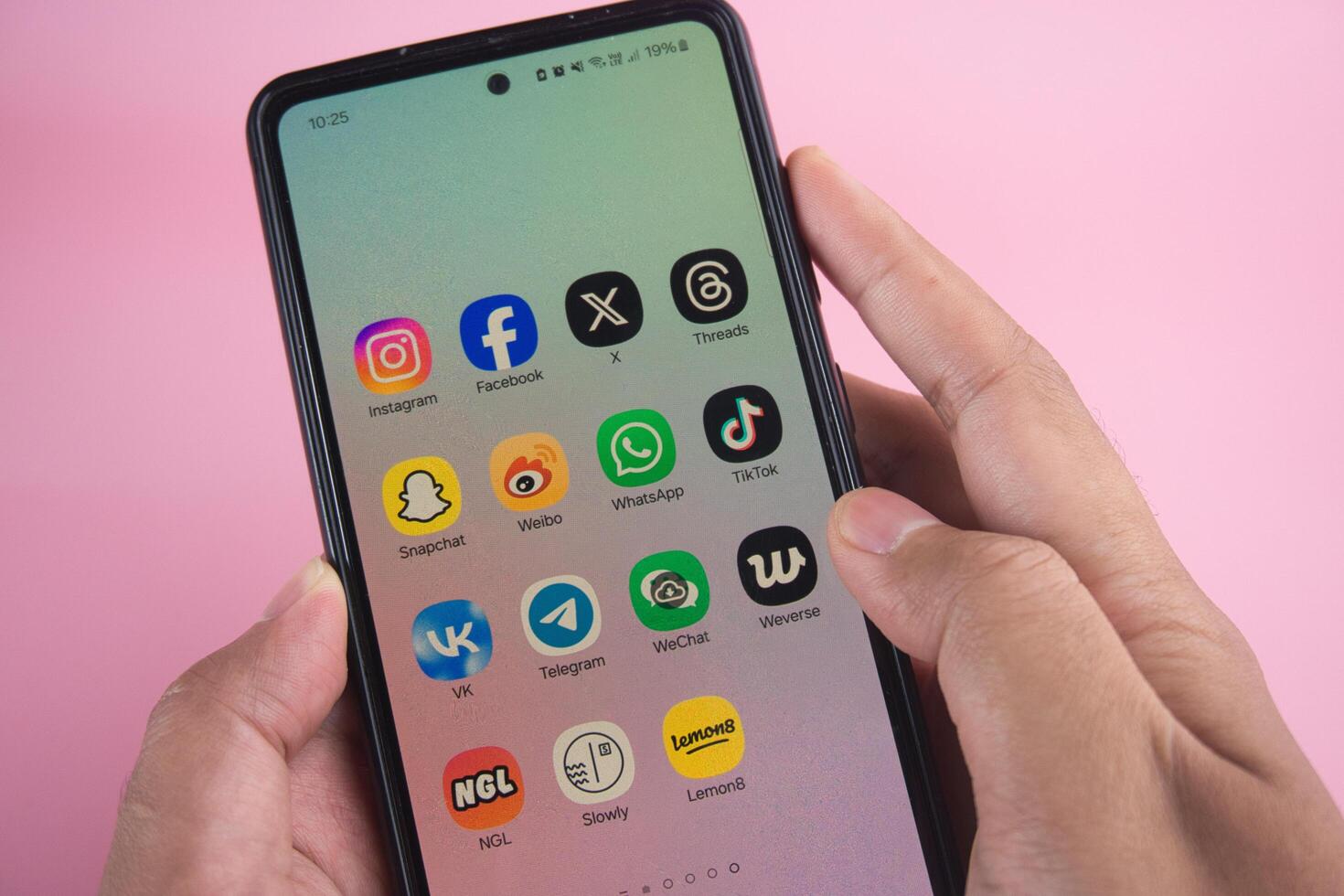 Close-Up of Smartphone Displaying Popular Social Media Applications on Pink Background photo