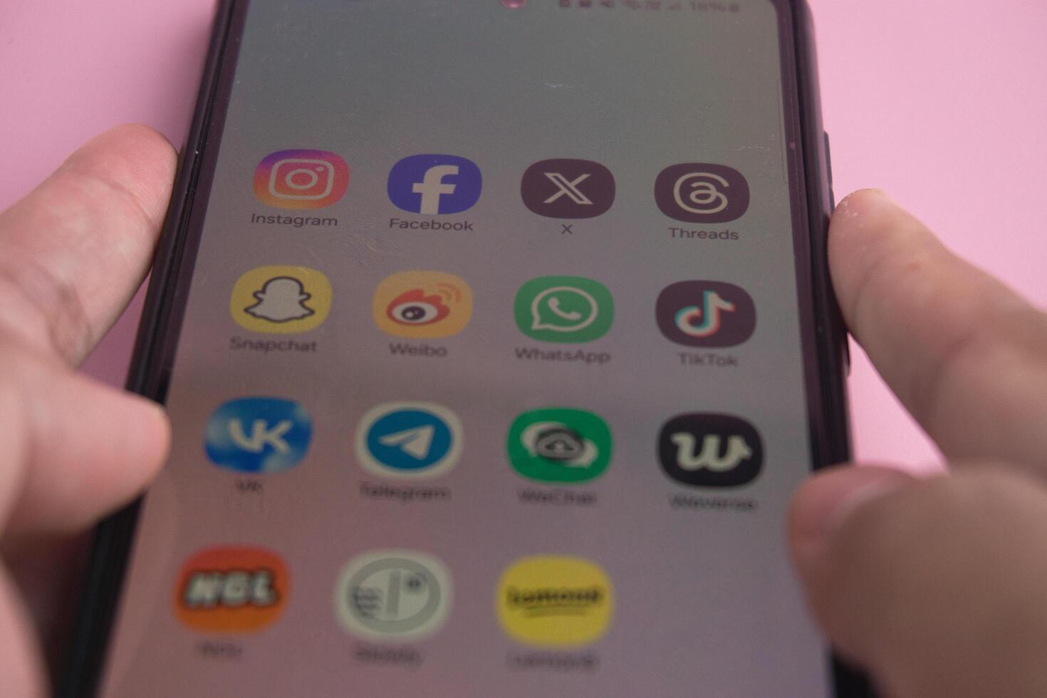 Close-Up of Smartphone Displaying Popular Social Media Applications on Pink Background photo
